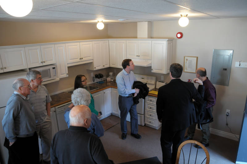 Members of the Cornwall Wesleyan Church show off their new disaster relief center on Feb. 28, 2015, which will house a family of four for up to a month. Rev. Larry Blaikie (black suit) shows of the kitchen to MP Executive Assistant Eric Duncan, center, while Acting Cornwall Mayor Carilyne Hebert (green jacket) listens. (Cornwall Newswatch/Bill Kingston)