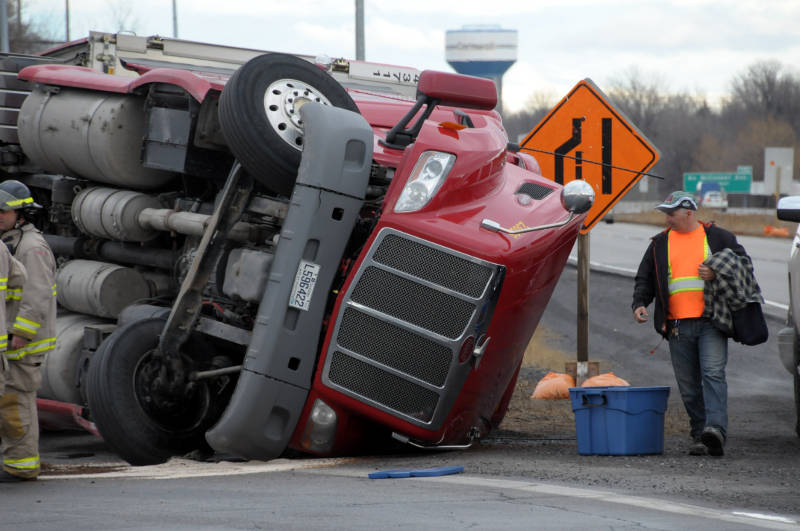 This unidentified truck driver looks at what's left of his rig after the truck tipped over on the Highway 401 westbound on-ramp at Brookdale Ave. on April 20, 2015. The trucker was not injured. (Cornwall Newswatch/Bill Kingston)