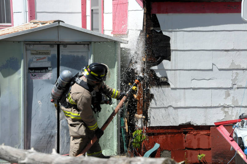 A firefighter shoots water inside the enclosed porch of this home on Vimy Ave. on May 21, 2015. The platoon chief credits the quick actions of the residents for stopping a potentially bigger disaster. (Cornwall Newswatch/Bill Kingston)