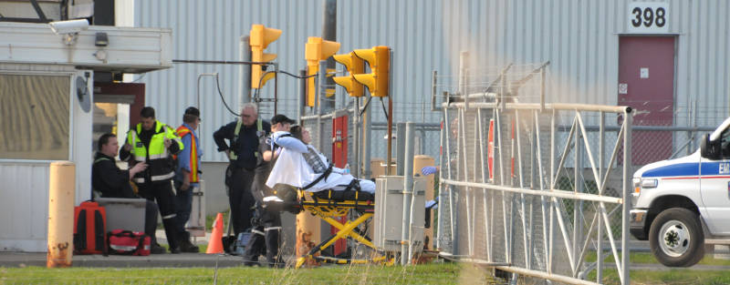 A woman is taken away by paramedics on a stretcher while another man, seated, is checked over by paramedics. Emergency crews were called May 1, 2015 after an explosion and fire involving a tanker truck on the property. (Cornwall Newswatch/Bill Kingston)