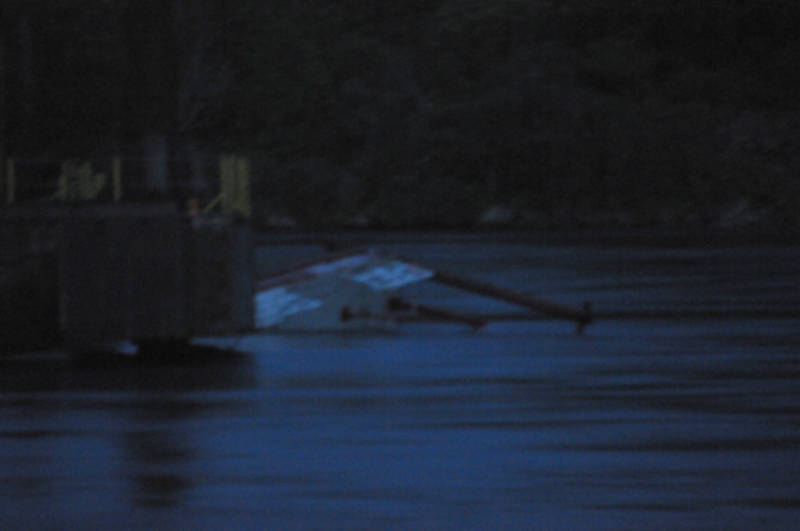 A portion of a tug boat (white) sticks out of the St. Lawrence River next to a barge after capsizing around 9 p.m. June 22, 2015. This was the second tug to go under trying to position the barge for work on the north channel bridge. Transport Canada is leading a plan for righting the vessels, according to the Ontario Ministry of Environment. (Cornwall Newswatch/Bill Kingston)