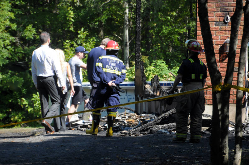 A young man, who identified himself as 'Tyler', is led into the scene by O.P.P. investigators and the Ontario Fire Marshal investigator to survey the damage. The man told investigators he grew up in the home. (Newswatch Group/Bill Kingston)