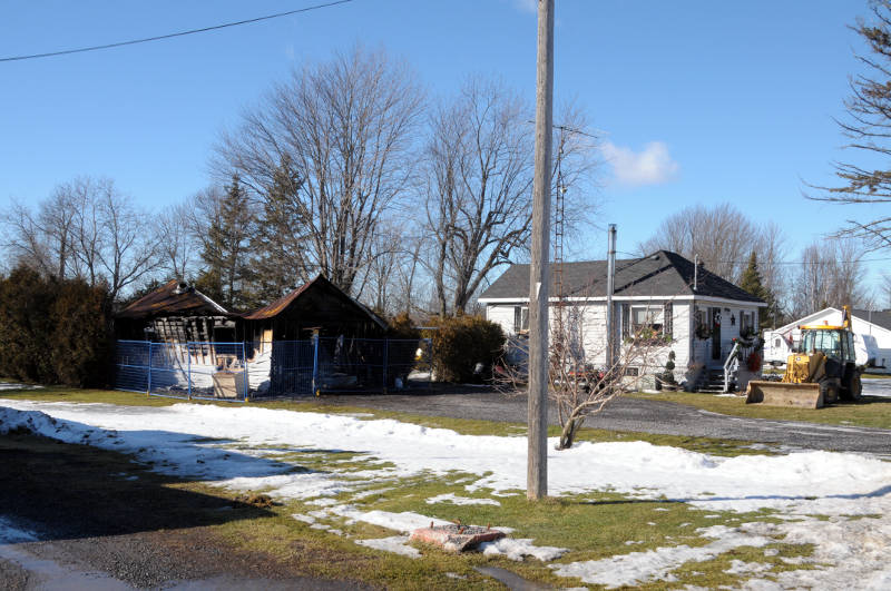 A garage fire at this Osnabruck Center, Ont. home on Jan. 28, 2016 gutted the building and melted the siding on the nearby house. A man was treated for burns to his face and arms after the flash fire. (Newswatch Group/Bill Kingston)